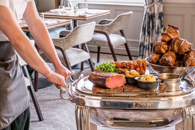 Waiter wheels roast dinners on a trolley in a restaurant